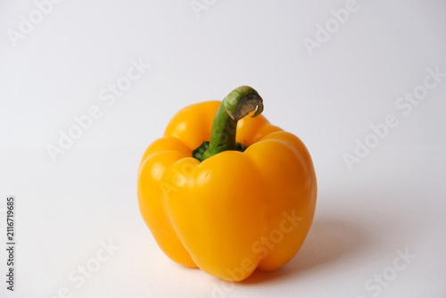 Fotografie Single yellow bell pepper rests on plain white surface