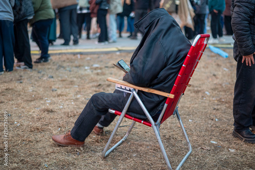 Fotografie Person sitting in chair absorbed in smartphone