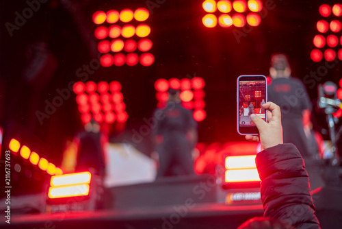 Hand holding smartphone recording live concert performance