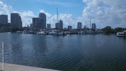 Time lapseView from Albert Whitted Playground into south yacht basin in St. Petersburg, FL. Towards marina, docked boats and Skyline of downtown. Masts and sails against a blue sky. Calm blue water wi