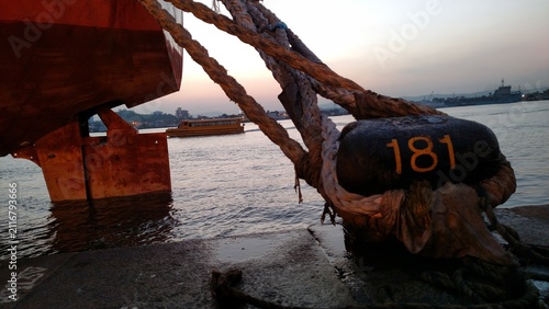 Принти на полотні Mooring bollard 181 with ropes and ship hull at dusk in Santos Port, Brazil