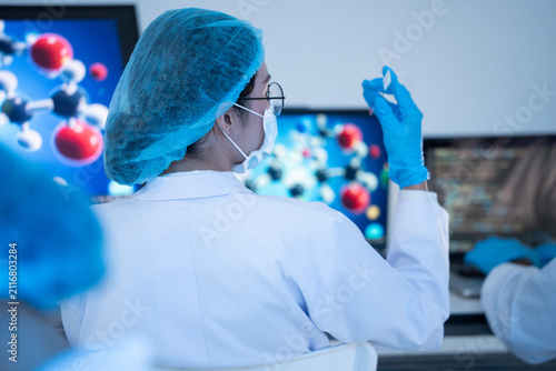 Fotografie Back view of female scientist raising glass slide sample to examine clinical dat