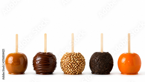Five toffee apples standing in a spaced row, each with a different coating of caramel, dark chocolate, crushed nuts, black. Generative AI photorealistic Halloween studio image isolated on white.