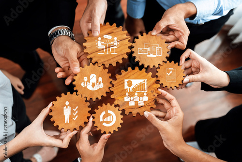 Фотография A diverse group of professionals collaborates over wooden gears symbolizing business management, innovation, and teamwork in a modern workplace setting