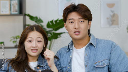 Obraz na płótnie Young Asian Couple Looking Shocked and Fearful While Watching Television