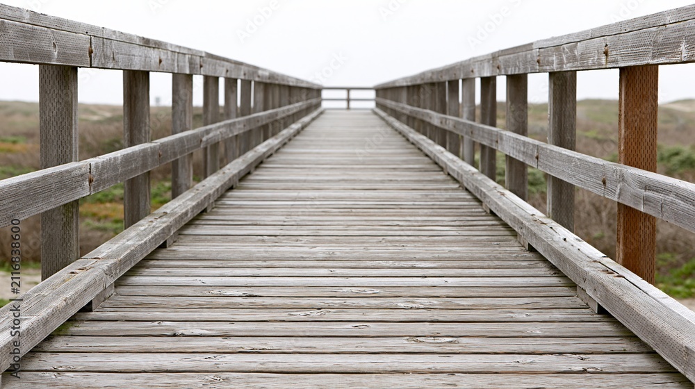 Obraz premium Wooden boardwalk leading to the ocean on a cloudy day, perfect for travel and coastal themes