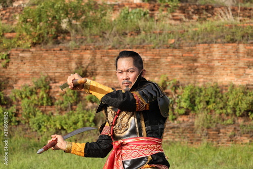 Quadro su tela Thai Warrior in Traditional Armor Holding Dual Swords at Ancient Temple