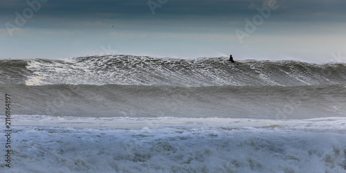 Obraz na płótnie Surfer paddling out in big waves
