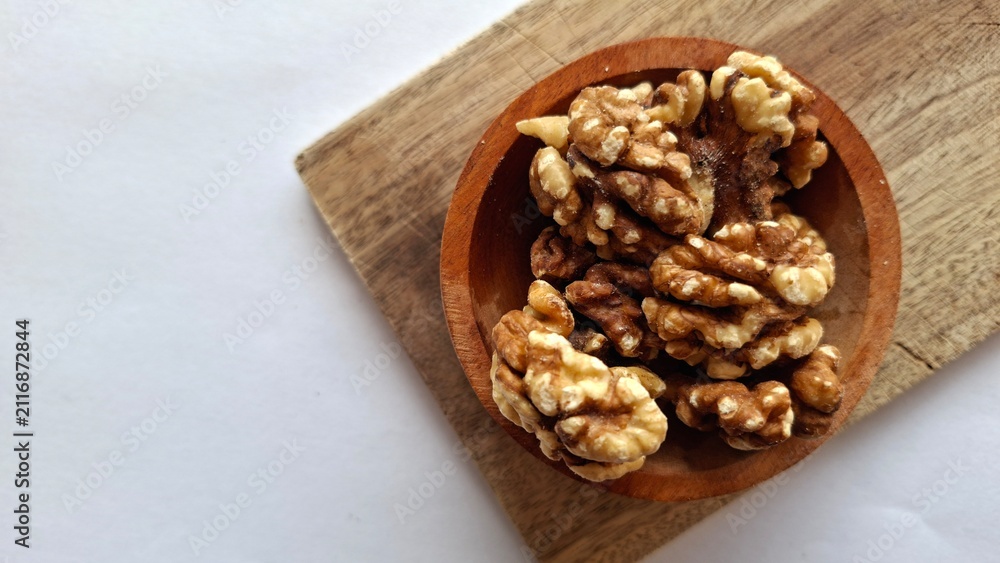 Fototapeta premium Photo of a collection of walnuts in a wooden bowl on a wooden cutting board