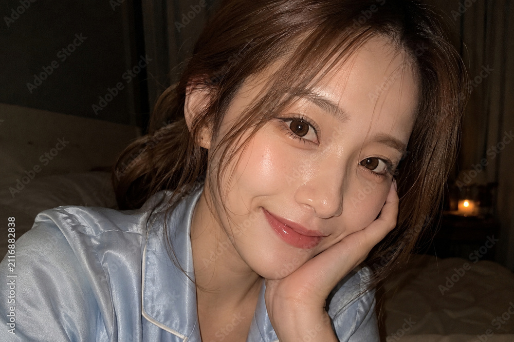 Fototapeta premium 夜の寝室で頬杖をつく青いパジャマ姿の女性
