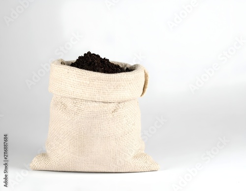 Burlap sack filled with dark organic soil isolated on a white background