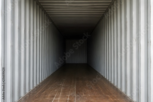 Empty Shipping Container Interior Reveals Ribbed Steel Walls And Heavy Wooden Flooring Fading Into Darkness