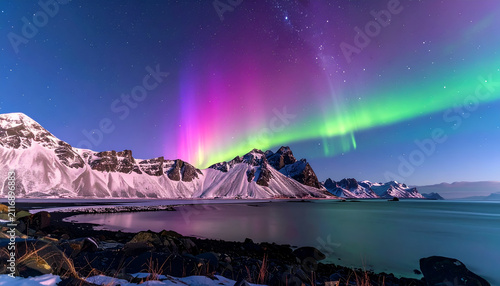 A stunning nighttime landscape featuring a vibrant display of the aurora borealis, illuminating mountains and a calm body of water