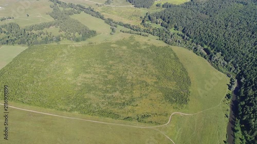 High altitude drone flying backward over meadow