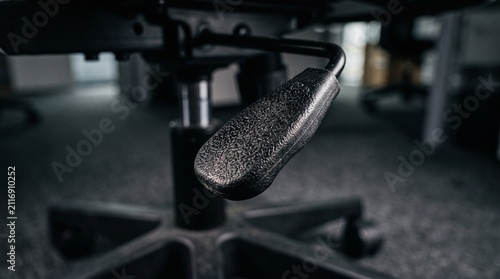 Close-up of an ergonomic office chairs height adjustment lever and base, showcasing its textured surface and mechanical components.