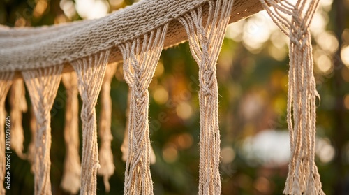 Close-up of a decorative macrame fringe on a hammock with blurred green background.