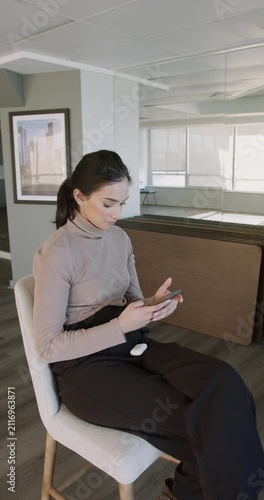 Young businesswoman texting on smartphone in office