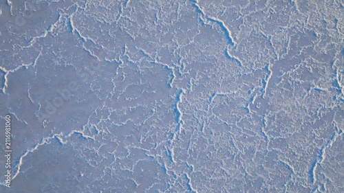 Top-down aerial view of Larnaca Salt Lake in Cyprus. Cracked white salt patterns create an abstract natural texture.