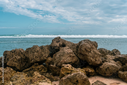 Rocky Beach Coastline With Ocean Waves And Cloudy Sky Over Sandy Shoreline