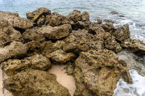Rugged Rocky Shoreline With Weathered Coral Rocks and Gentle Ocean Waves on Sandy Beach