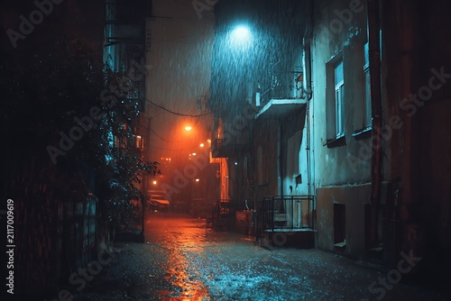 A rainy night in a dark alleyway with old buildings and street lights creating a moody atmosphere.