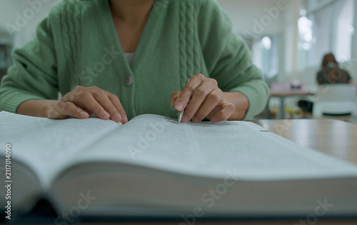 Asian woman reading book at library.