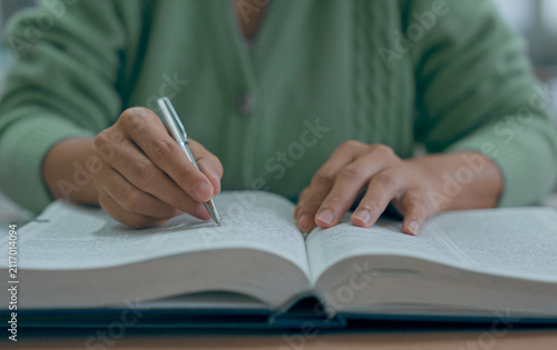 Asian woman reading book at library.