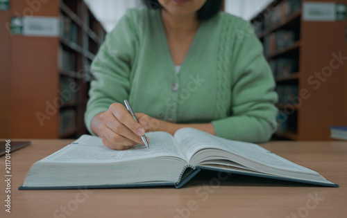 Asian woman reading book at library.