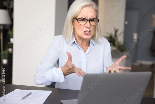 Quadro su tela Angry annoyed older businesswoman ceo boss leader scold shame staff on video conference using laptop webcam