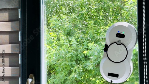 Foto Window cleaning robot mounted on glass surface with greenery background and mode