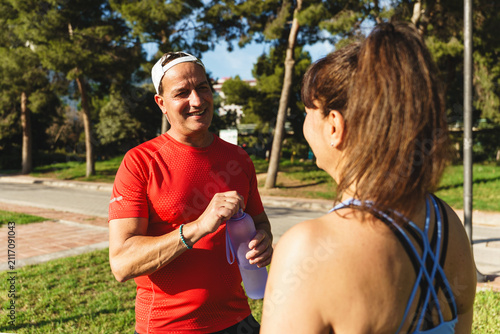 фотографія Senior couple taking a break from exercising, talking and hydrating with water