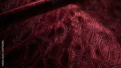 Luxurious dark red velvet fabric with an embossed geometric pattern, creating an elegant textile background with rich texture and subtle light play
