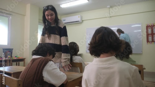 The teacher is teaching young children in a class at school.