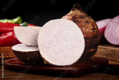 Obraz na płótnie Fresh taro root slices on wooden board with peppers and onion