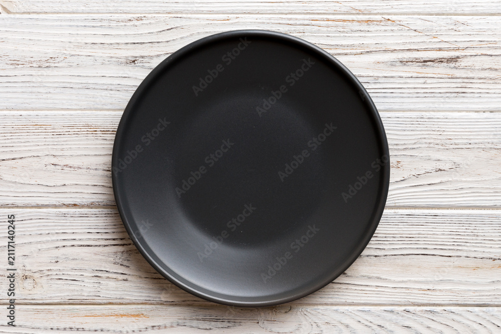 Obraz premium Top view of black plate on wooden background. Empty space for your design
