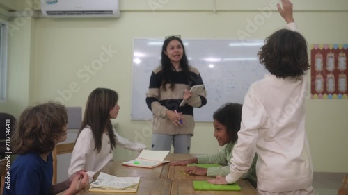The teacher is teaching young children in a class at school.