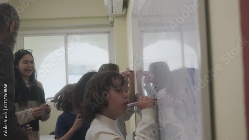 The children are drawing on the whiteboard in the classroom.