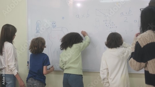 The children are drawing on the whiteboard in the classroom.