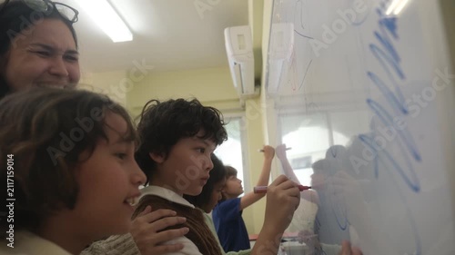 The children are drawing on the whiteboard in the classroom.