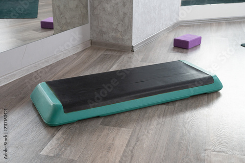 Fitness aerobic step platform in gym environment with mirror and yoga block