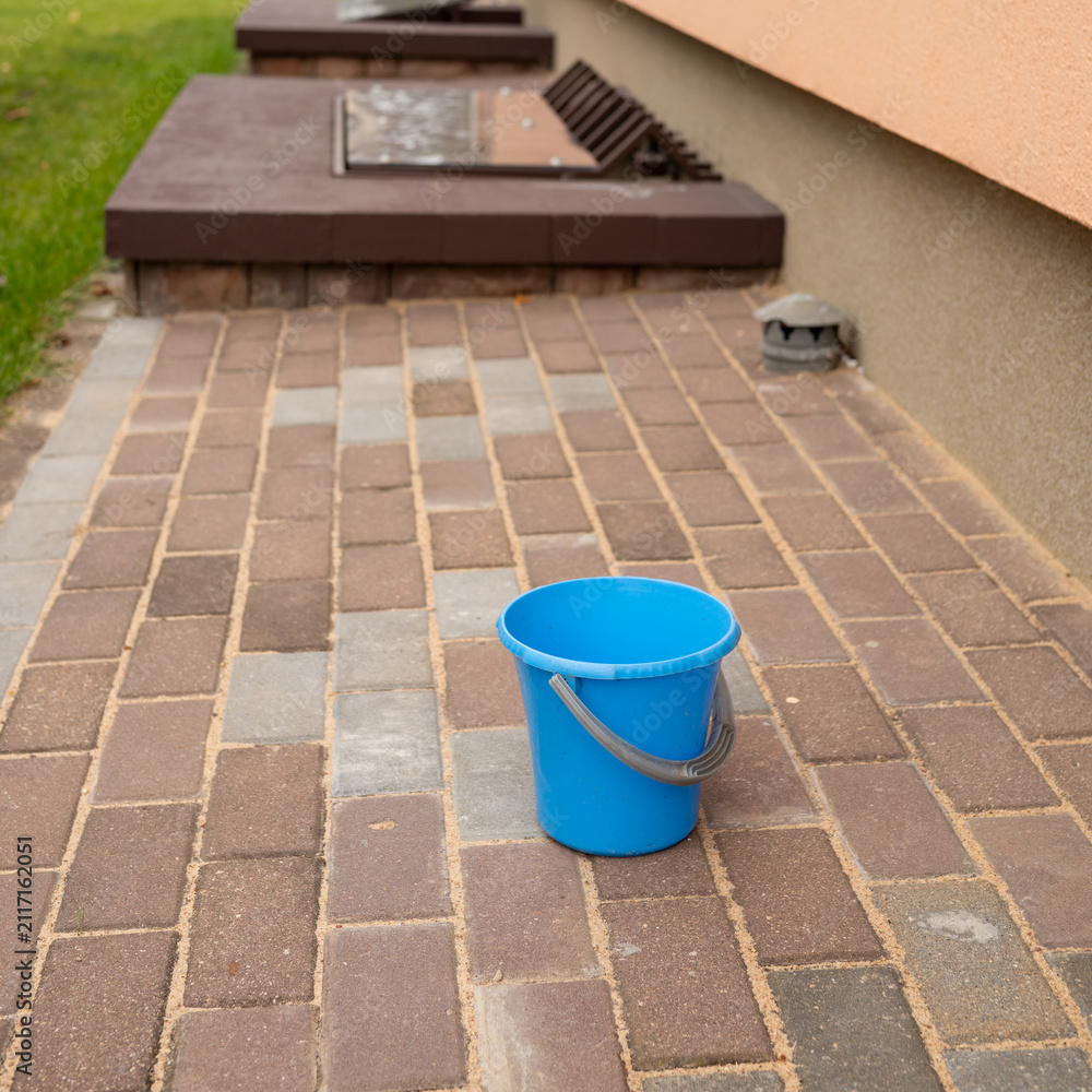 Naklejka premium Blue bucket on brick patio of residential building