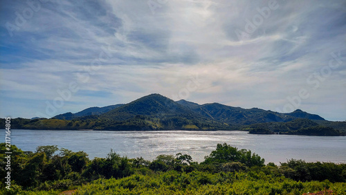 Fotografie A wide angle of rolling green mountains with the sun creating a shimmering refle
