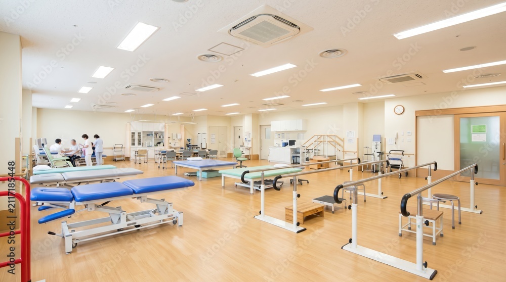 Fototapeta premium Spacious physical therapy room inside a modern medical rehabilitation center equipped with treatment beds, parallel bars, and exercise equipment for patient recovery and health care services