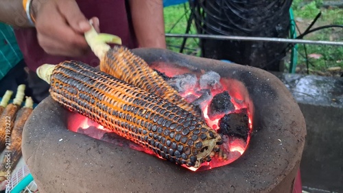 Obraz na plátně Roasting fresh raw corn over a charcoal fire,Roasted corn is a delicious and healthy snack