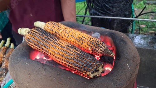 Roasting fresh raw corn over a charcoal fire,Roasted corn is a delicious and healthy snack.It is cooked over hot charcoal until lightly charred. People enjoy it with lemon, salt, and spices for a tast