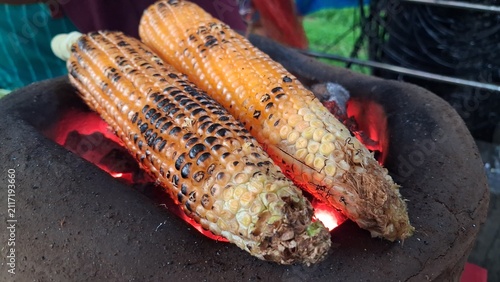 Konstfotografi Roasting fresh raw corn over a charcoal fire,Roasted corn is a delicious and healthy snack