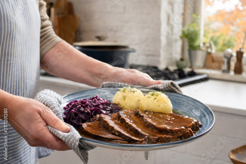 Disfrutar de un plato tradicional alemán servido con carne, puré y ensalada de col roja