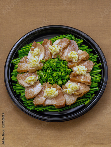 Delicious pork belly slices with garlic and chives on a black plate