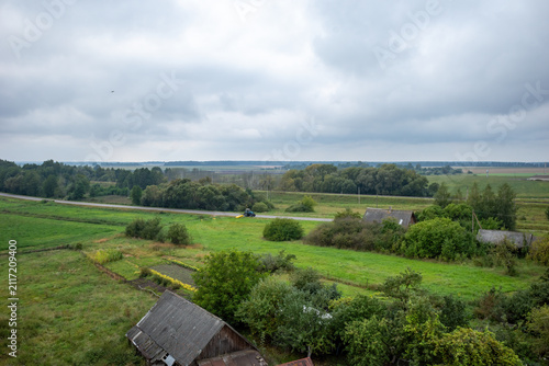 Aerial view of a rural landscape with old houses, green fields, and a road.