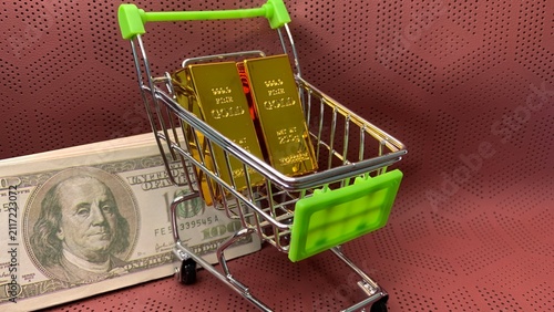 Foto Gold bars and a hundred-dollar bill displayed in a miniature cart representing d